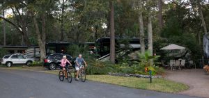 luxury RV resorts - people biking on a paved path in front of motor homes 