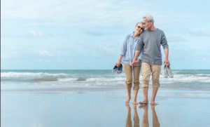Beachfront luxury RV resorts - Age, Travel, Tourism and people concept - happy senior couple holding hands and walking on summer beach