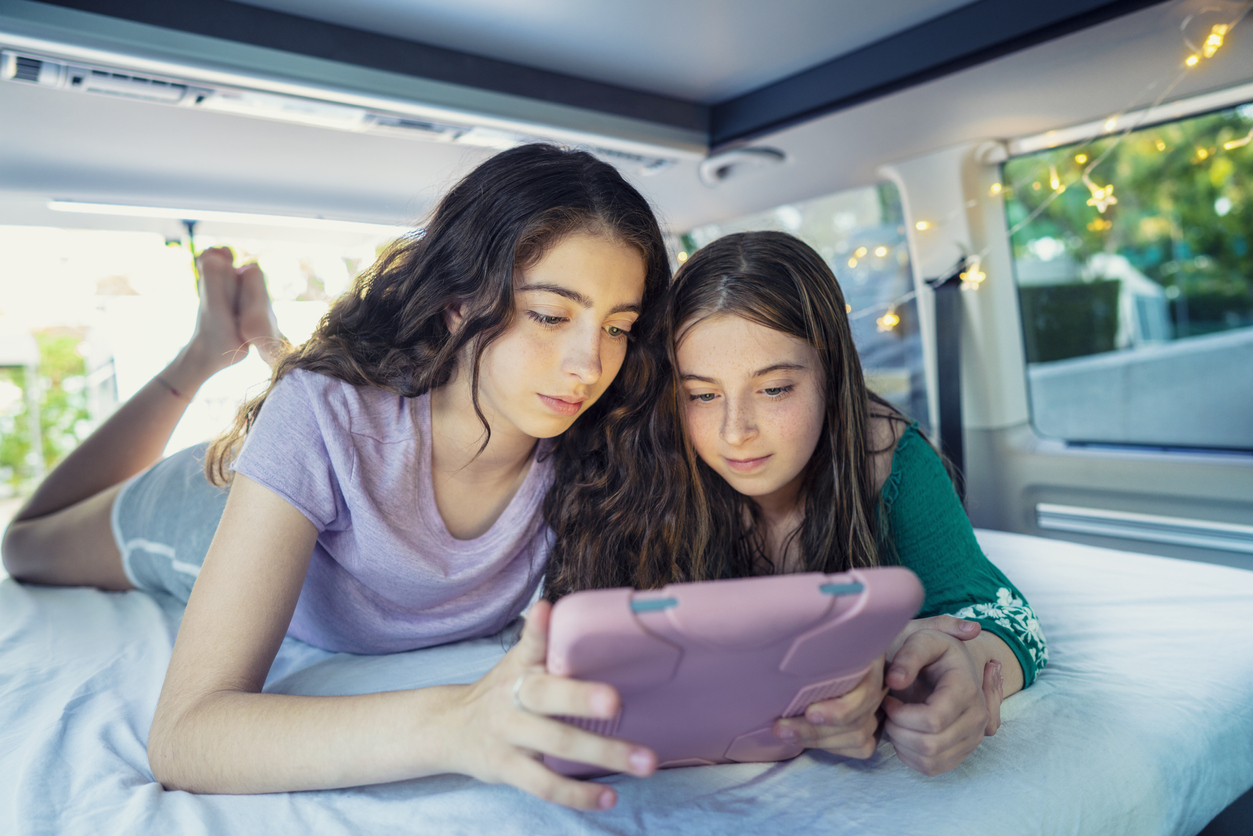 roadschooling - Girls playing with technology in camper van indoor with tablet
