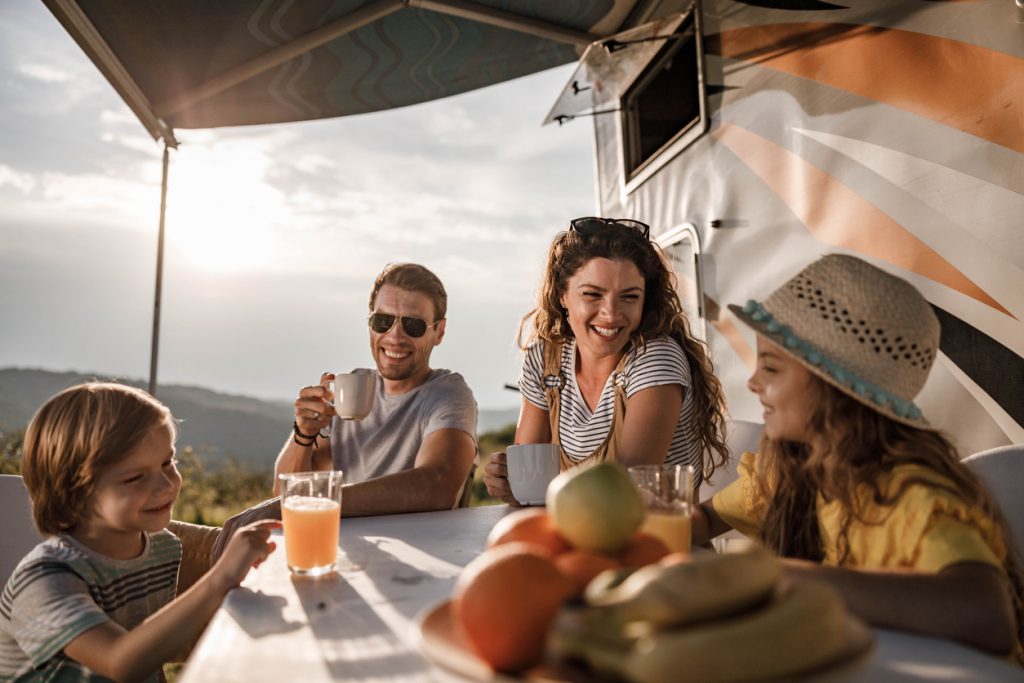 Happy parents and their small kids communicating while spending a spring day on camping. Focus is on man.