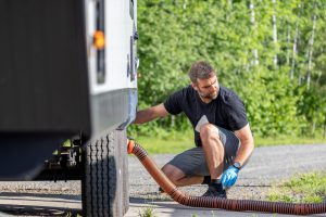 Man Emptying RV Sewer at Dump Station After Camping