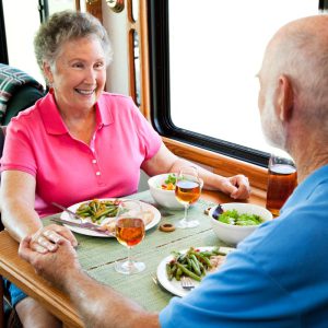Senior couple sitting at the RV dinette with a meal on the table. 