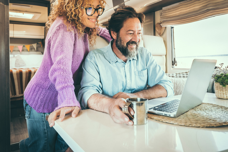 Couple looks at renting your RV information on a laptop in their camper.